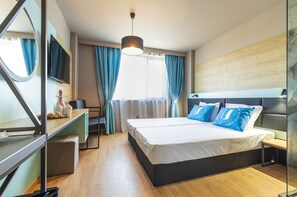 A modern hotel room with a large bed, a desk, a mirror, and a TV. - Urban Hotel (Plovdiv)