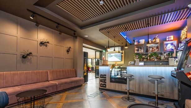 A modern bar area with a counter, stools, and a seating area with a sofa and tables. - Urban Hotel (Plovdiv)