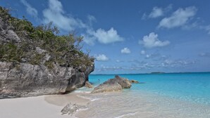A beach with clear turquoise water, white sand, and rocky outcrops. - Private Beachfront Luxury Villas with Dock & Heated Pools – Perfect for 10 Guests (Exuma)