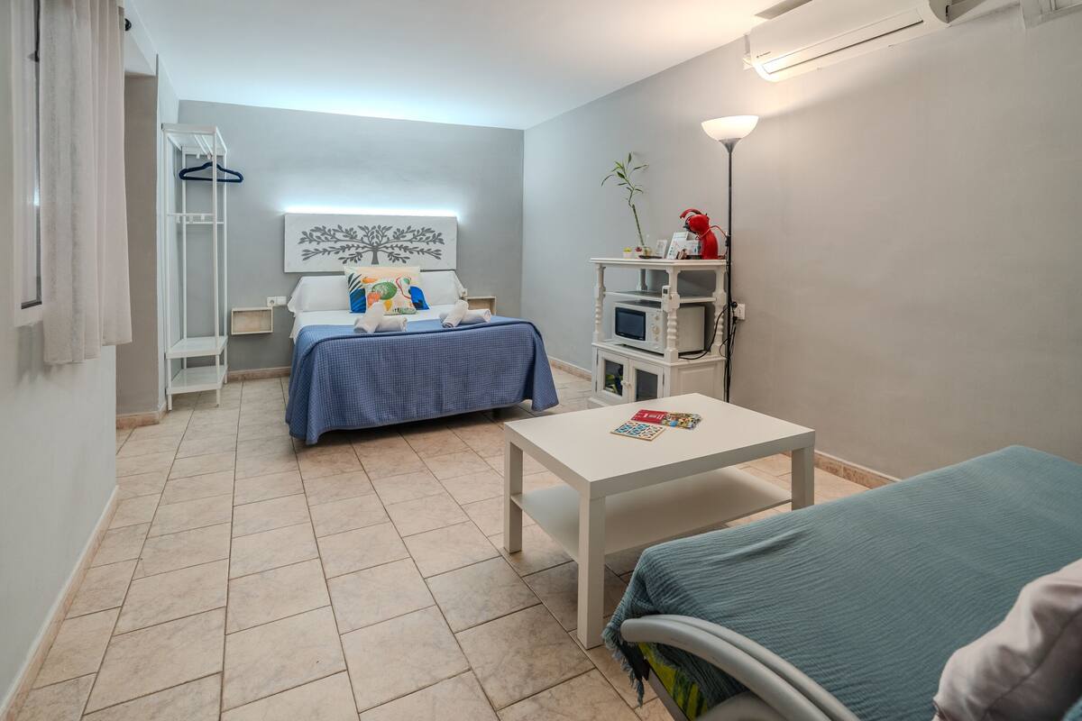 Ein Schlafzimmer mit einem Bett, einem Nachttisch und einem kleinen weißen Tisch mit einer Zeitschrift.