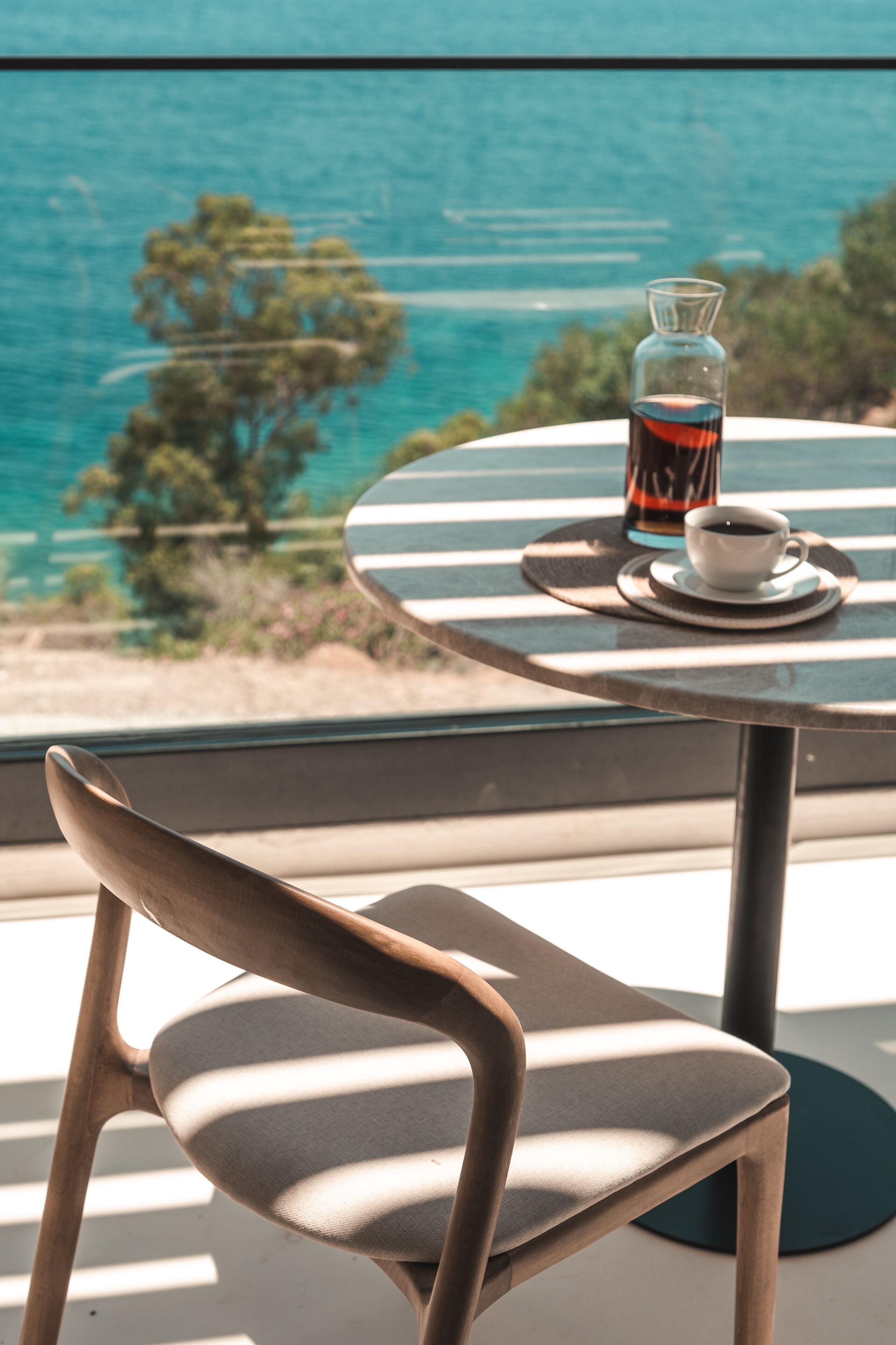 A chair and a table with a glass of drink and a cup, overlooking a scenic view.