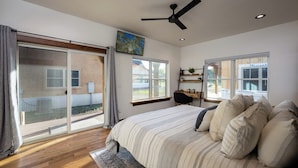 A bedroom with a large bed, a ceiling fan, and a view through a sliding glass door to the outside. - Downtown Location, Walk to Town, Close to River, AC (Pagosa Springs)