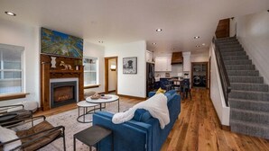 A spacious living room with a fireplace, a blue sofa, and a staircase leading to the upper floor. - Downtown Location, Walk to Town, Close to River, AC (Pagosa Springs)