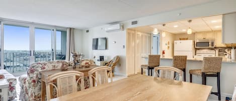 Een moderne woonkamer met een eetgedeelte, grote ramen en uitzicht op de stad.