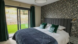 Ein Schlafzimmer mit einem großen Bett, einem Nachttisch, einem Fenster mit Vorhängen und einer Wand mit Muster.