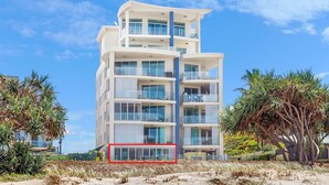 Un hôtel à plusieurs étages doté de balcons, d’un espace piscine et d’un aménagement paysager de style tropical.