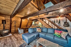 A cozy cabin interior with a sectional sofa, a fireplace, and a staircase leading to an upper level. - Reindeer A Frame Cabin, hot tub, pet friendly (South Lake Tahoe)