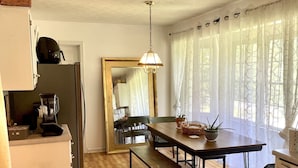 Una cocina compacta con encimera de madera, refrigerador integrado, cafetera y una mesa con bancos.