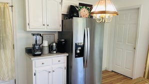 Una cocina con un refrigerador de acero inoxidable, una cafetera, una licuadora y una jarra para café.