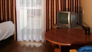 A room with a bed, a table with a television, and curtains. - OSW BALTIC SOPOT (Sopot)