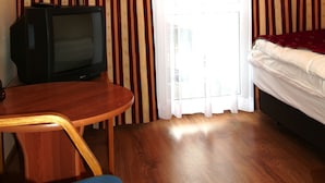 A hotel room with a wooden floor, a bed, a television on a wooden table, and curtains with a striped pattern. - OSW BALTIC SOPOT (Sopot)
