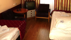 A hotel room with a bed, a chair, a small table, a television, and curtains. - OSW BALTIC SOPOT (Sopot)