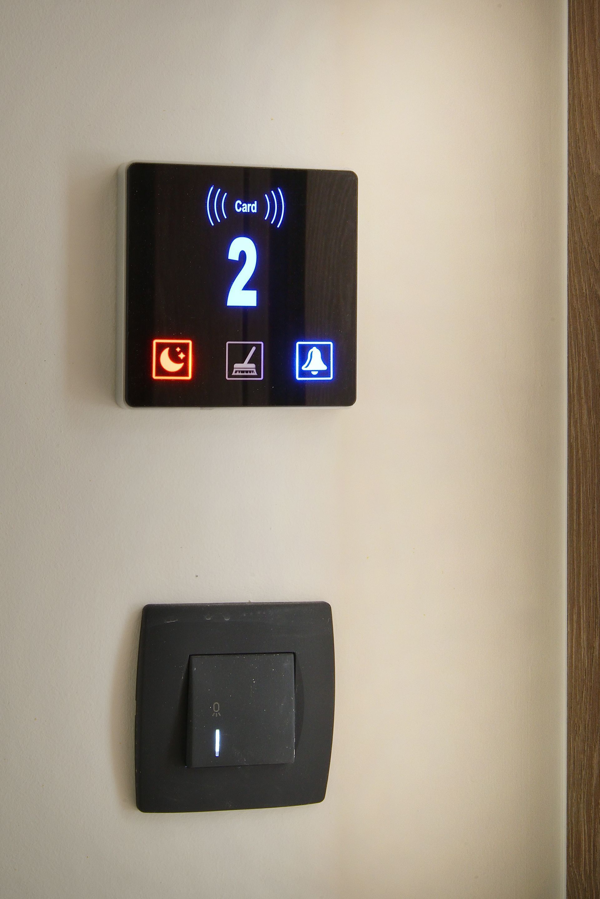 A digital card reader with a display showing the number 2 and icons for card, room, and bell. Below it is a physical keycard slot.