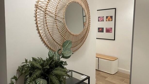 A modern interior with a circular woven wall art, a potted plant, and a framed picture of flowers. - Acogedor piso cerca al Parque El Retiro FREE WIFI (Madrid)