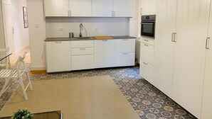 A compact kitchen with white cabinets, a built-in oven, and a patterned floor. - Acogedor piso cerca al Parque El Retiro FREE WIFI (Madrid)