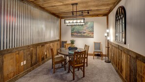 A dining area with a wooden ceiling, a round table, and chairs. There is a painting on the wall and a window with a decorative frame. - Downtown Bryson City 2 Bedroom Apartment, Perfect for Polar Express! (Bryson City)