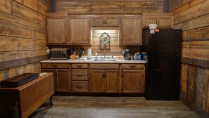 A kitchen with wooden cabinets, a black refrigerator, a microwave, and a wooden countertop. - Downtown Bryson City 2 Bedroom Apartment, Perfect for Polar Express! (Bryson City)