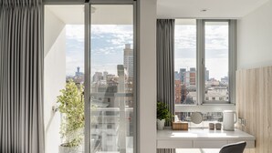 A modern room with a city view, a desk with a plant, a kettle, and a chair. - 1LI7E HOTEL (Taichung)