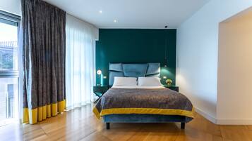 Ein modernes Schlafzimmer mit einem großen Bett, einem Kopfteil und einem Nachttisch mit Lampe.