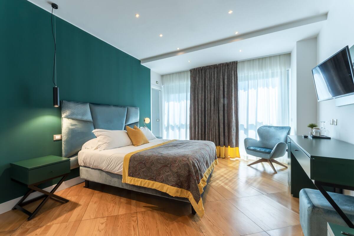 A modern hotel room with a large bed, a desk, and a chair.