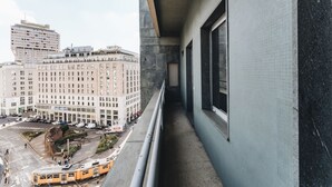 A narrow balcony with a view of a cityscape, including a large building with multiple windows and a tram in the foreground. - Missori Suites (Milan)