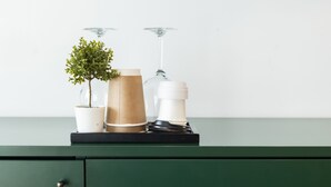 A green cabinet with a potted plant, a brown paper cup, and a glass bottle on top. - Missori Suites (Milan)