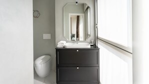 A modern bathroom with a white sink, dark vanity, and a large mirror. - Missori Suites (Milan)