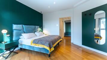 A modern bedroom with a large bed, a bedside table with a lamp, and a mirror on the wall.