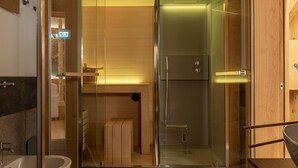 A modern bathroom with a glass shower enclosure, a wooden vanity, and a separate sink area.