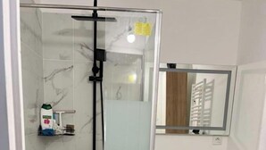 A modern bathroom with a glass shower enclosure, a white sink, and a wooden vanity. - Apartment near Paris (Noisy-le-Grand)
