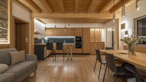 A modern kitchen with wooden cabinets, a central island, and pendant lighting. - Casera Cal De Mez Sot - Wellness Chalet (Chies d´Alpago)