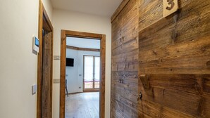 A hallway with wooden flooring and a wooden wall with a number '3' sign. - CHALET INES - Studio Apartment 3 (Vodo Cadore)