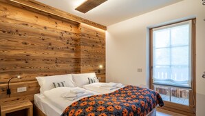 Ein Schlafzimmer mit einem hölzernen Kopfstück, einem großen Fenster und einem Bett mit floraler Dekoration.