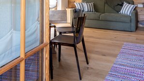 Ein Zimmer mit einer Holzwand, einem grünen Sofa, einem Holzesstisch und einem Stuhl.
