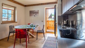 Une cuisine moderne dotée d’une hotte en acier inoxydable, de meubles en bois et d’un coin repas avec une table et des chaises.