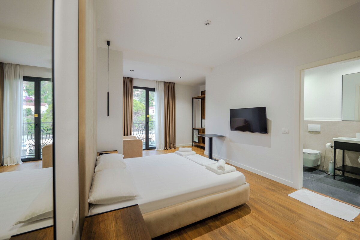 Habitación de hotel moderna con una cama grande, un televisor de pantalla plana, un escritorio y un baño.