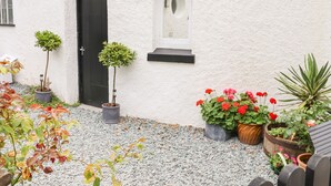 A courtyard with potted plants, a door, and a window. - Valley View (Teignmouth)