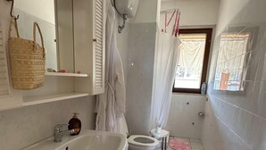 Une salle de bain comprenant un lavabo, deux toilettes, un miroir et un espace douche.