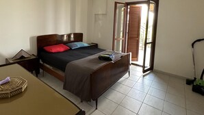 Une chambre à coucher avec un lit, un bureau et une fenêtre avec des stores.