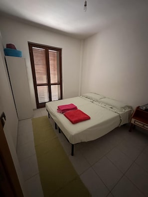 A small, clean room with a bed, a window with blinds, a desk, and a chair. - 2 Bed Villa - Sleeps 4 - Pets - Garden - Parking (Amendolara)