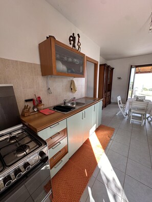 A modern kitchen with a gas stove, double sink, and wooden cabinets. - 2 Bed Villa - Sleeps 4 - Pets - Garden - Parking (Amendolara)