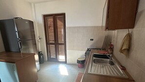 Une cuisine de taille réduite, équipée d’un réfrigérateur, d’une cuisinière, d’un évier et de meubles de rangement en bois.