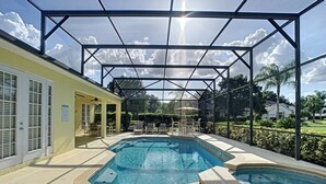 A pool area with a covered structure, outdoor seating, and a view of the surrounding landscape.