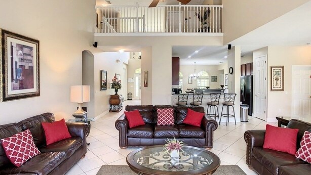 A spacious living area with two brown leather sofas, a glass coffee table, and a ceiling fan.