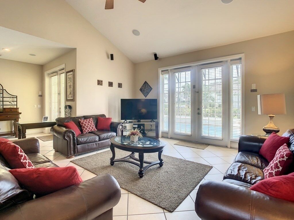 A spacious living room with a large TV, leather sofas, and a coffee table.