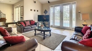 A spacious living room with a large TV, leather sofas, and a coffee table.