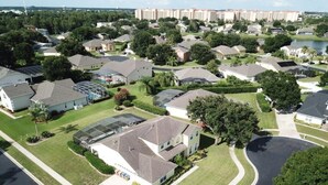 A residential area with houses, a curved road, and a body of water in the background.