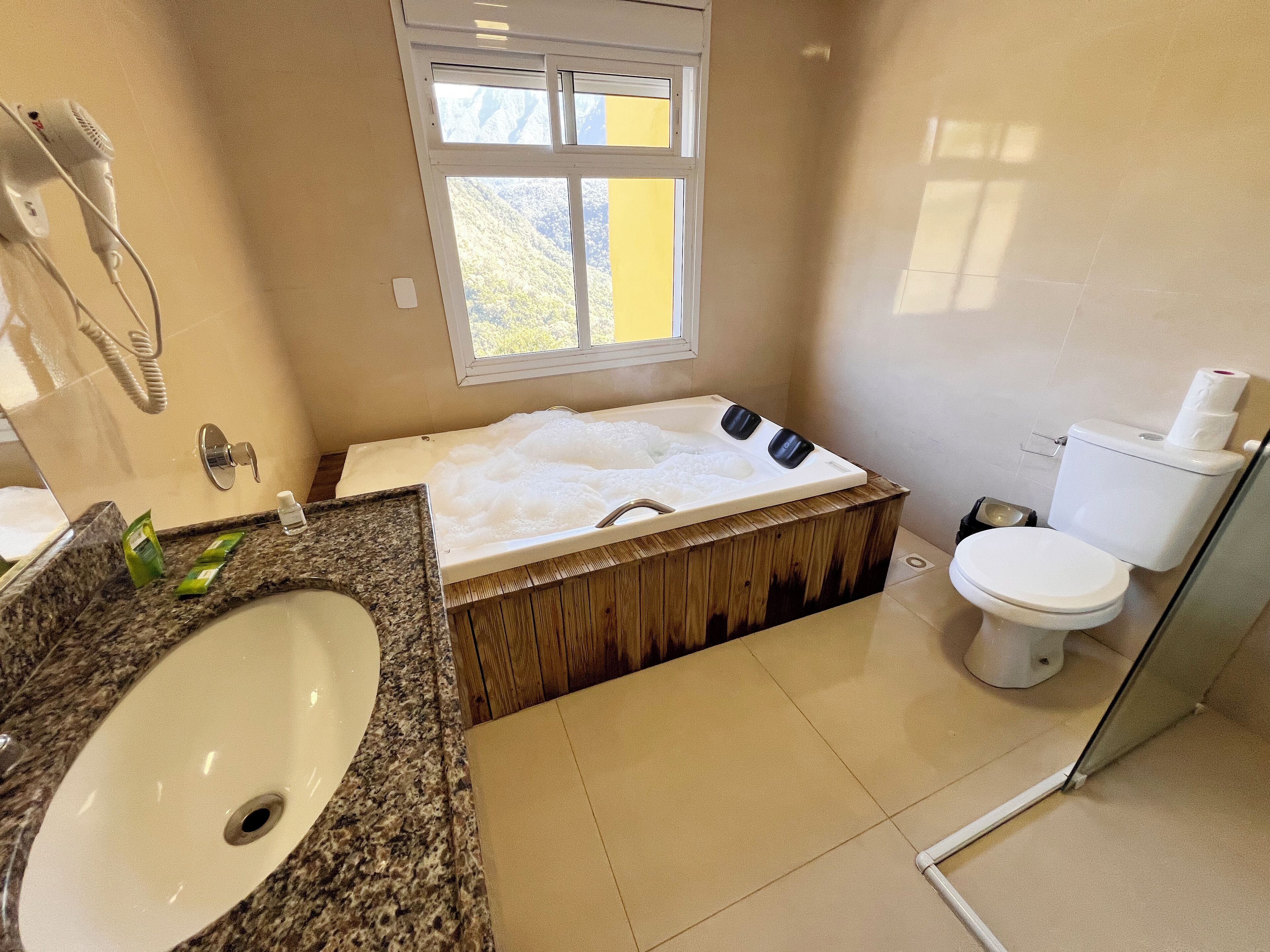 A bathroom with a large bathtub, a sink, a toilet, and a window.