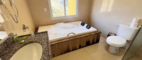 Un baño con una bañera grande, un lavamanos, un inodoro y una ventana.