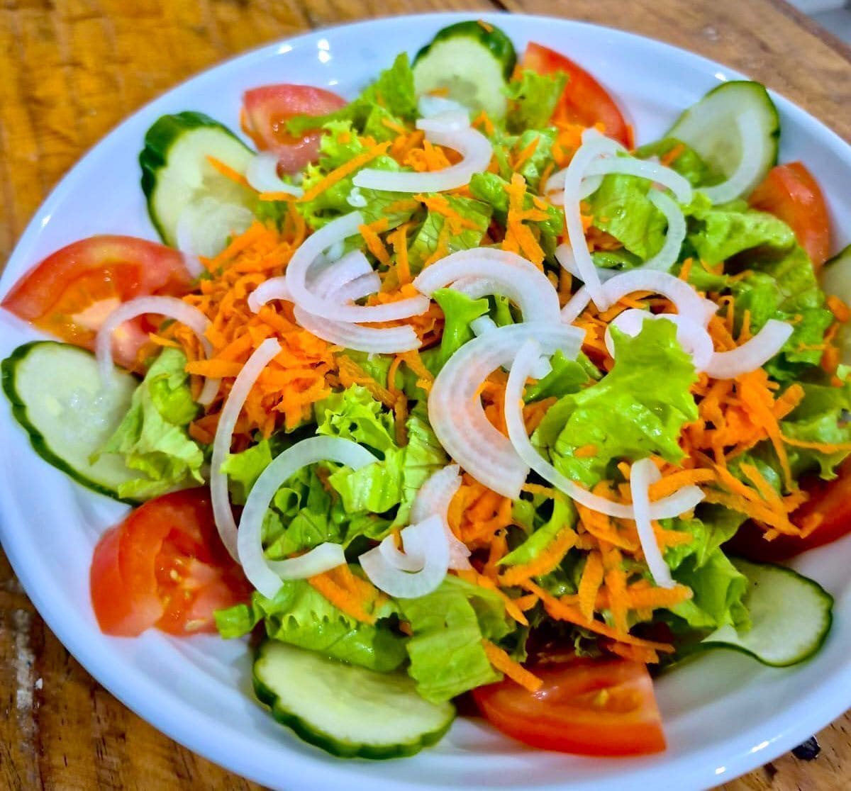A salad with lettuce, tomatoes, cucumbers, and shredded carrots.
